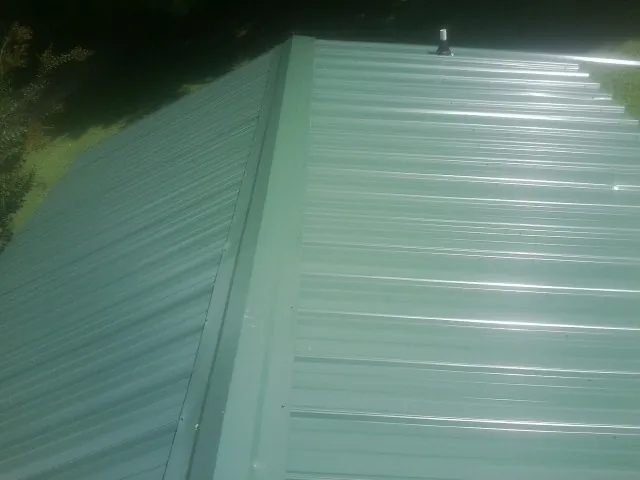 New green metal panels meeting at the ridge of a roof — Flat Roof Repair work by our crew in Kearny
