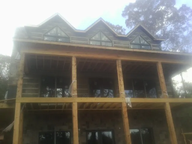 Dormers and porch framing on a large log home under construction — Roof Coating work by our crew in Kearny