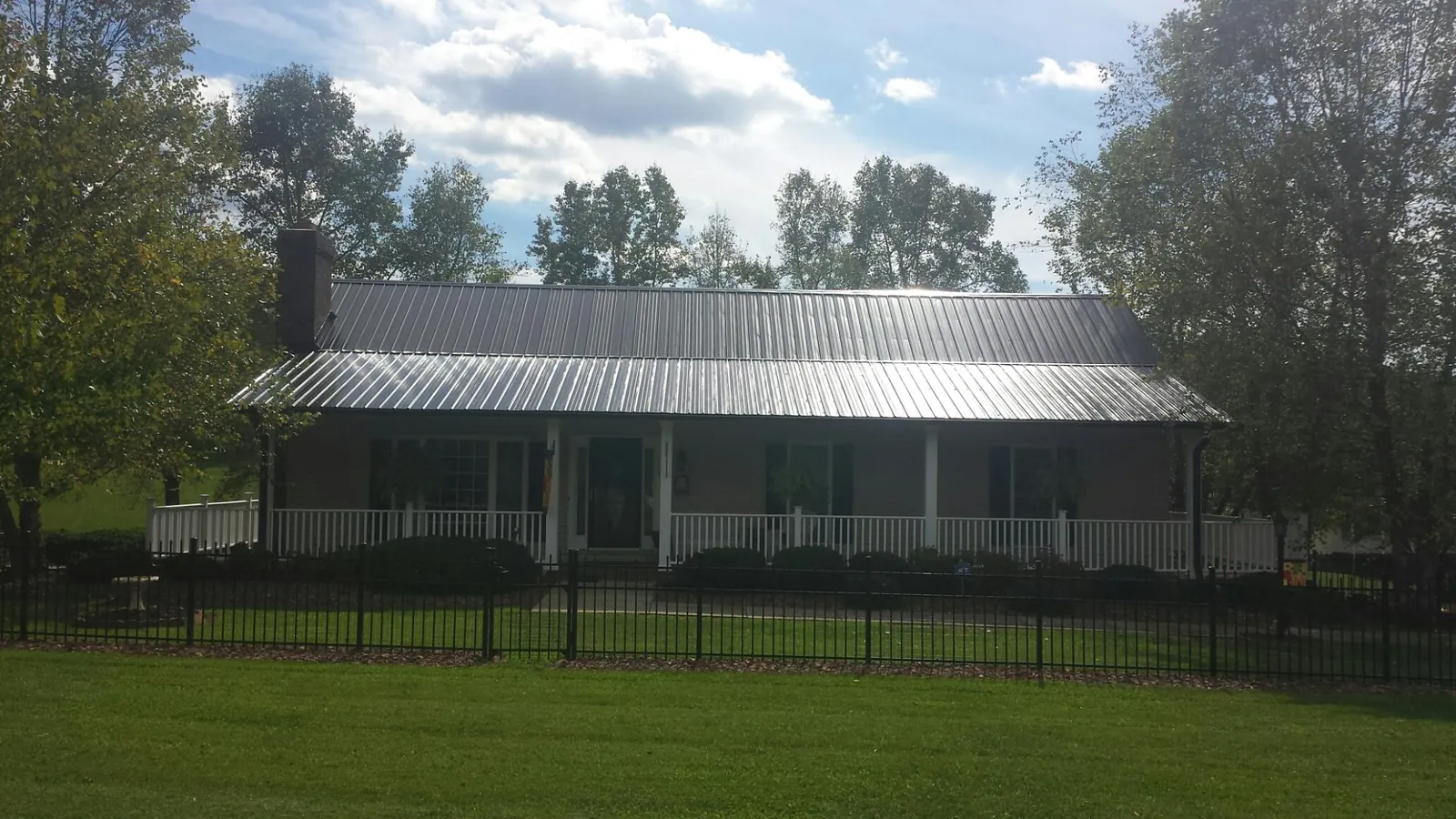 Gray metal roof on a brick ranch with a full width front porch — Gutter Guard Installation work by our crew in Kearny