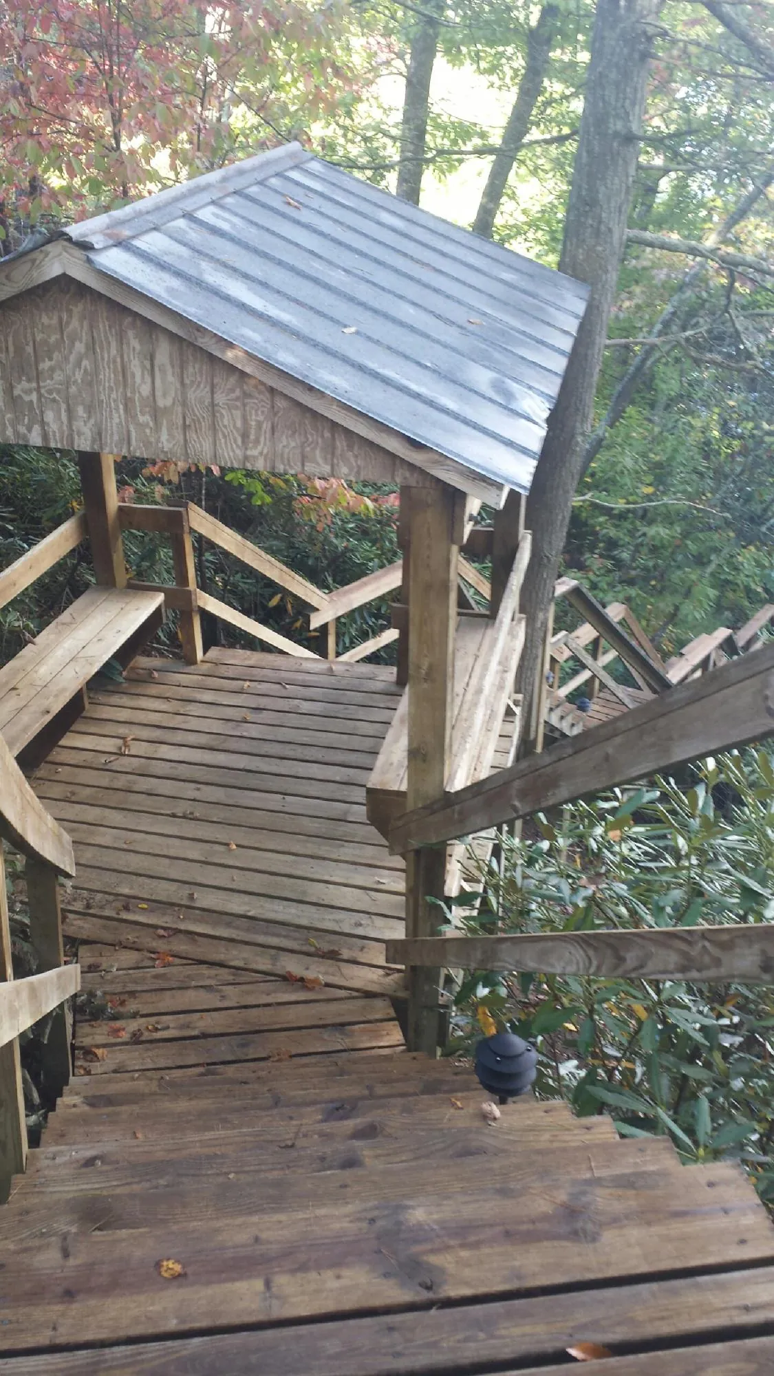 Metal roofed shelter over wooden steps on a wooded walkway — Skylight Repair & Installation work by our crew in Kearny