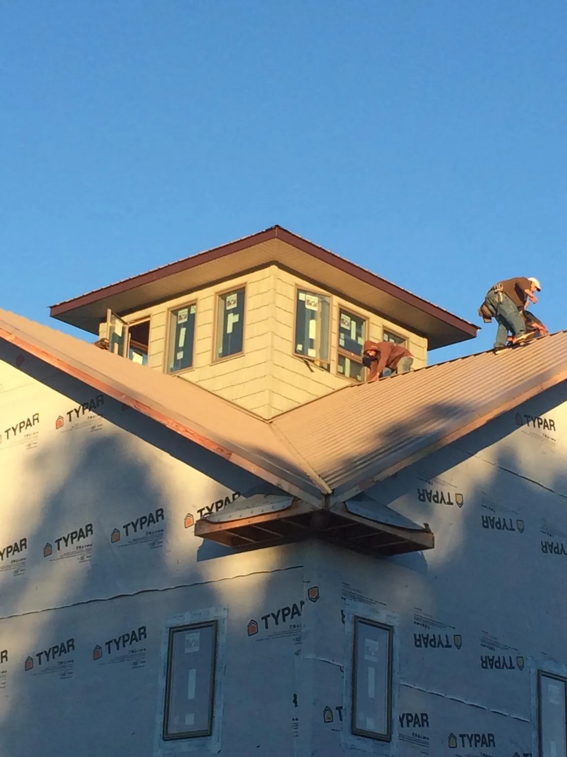 Roofers working around a rooftop cupola on a new metal roof at sunset — Roof Waterproofing in Kearny by Roofing Brothers